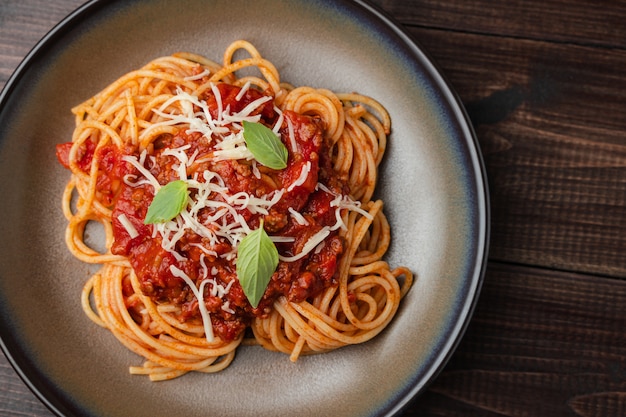 Salsa boloñesa de espagueti o salsa de tomate en una tabla de madera oscura