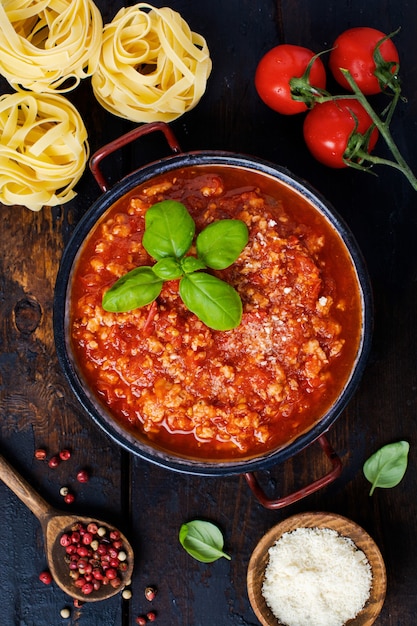 Salsa boloñesa italiana tradicional en cacerola un viejo fondo de madera oscura. Vista superior, espacio de copia