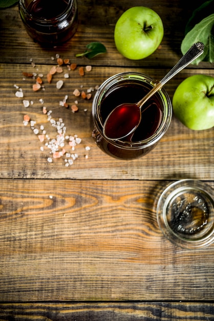 Salsa casera de caramelo clásico salado oscuro, con manzanas verdes, fondo de madera y azul oscuro,