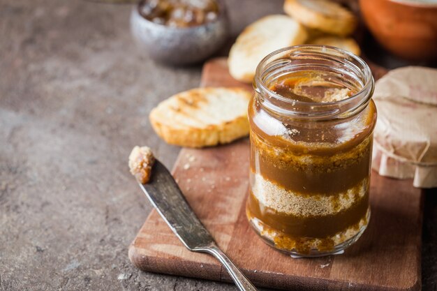 Salsa casera de caramelo salado con galletas en tarro sobre fondo rústico.