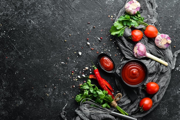 Salsa de chile ketchup con tomates. Salsa roja picante. Sobre un fondo de piedra negra.