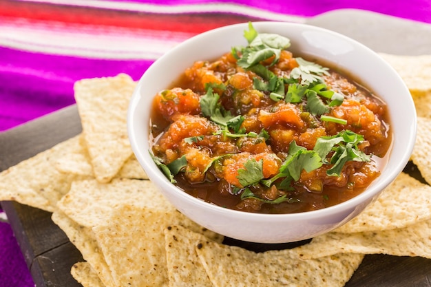 Salsa fresca en un tazón blanco con chips de tortilla de maíz blanco.