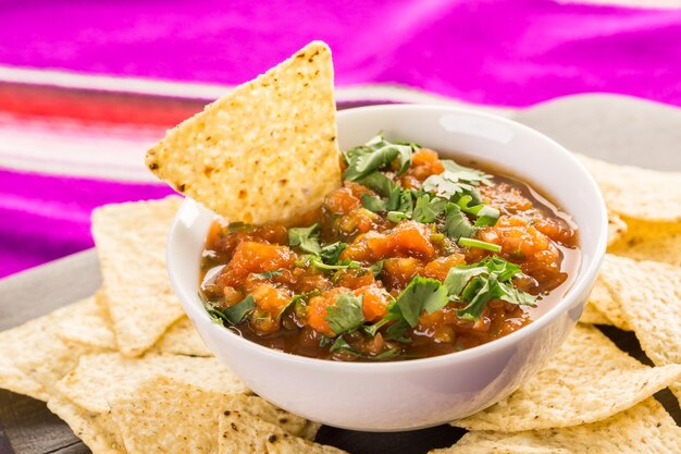 Salsa fresca en un tazón blanco con chips de tortilla de maíz blanco.