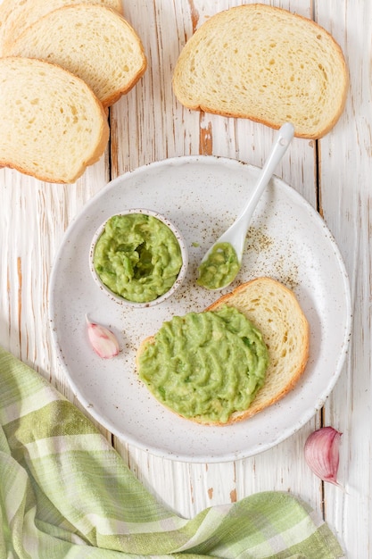 Salsa de guacamole mexicana tradicional latinoamericana y sándwiches de aguacate sobre fondo de madera clara