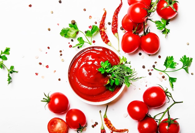 Salsa de ketchup picante de tomate con tomates cherry en un tazón en la vista superior de fondo de comida blanca