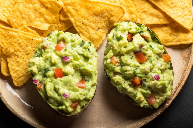 Salsa latinoamericana tradicional guacamole en chips de nachos mexicanos de medio aguacate cortado