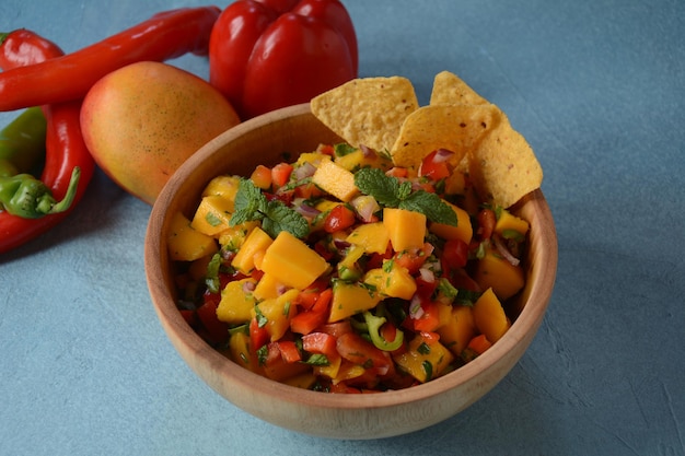 Salsa con mango, hierbas, cebollas y pimientos, chips de maíz de cerca en un bol. Comida mexicana.