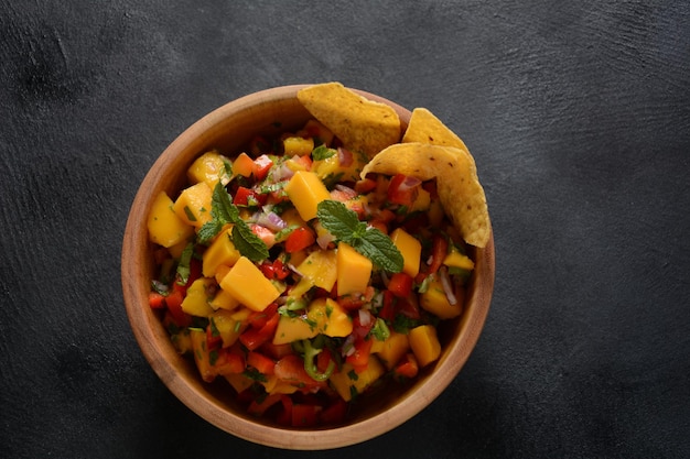 Salsa con mango, hierbas, cebollas y pimientos, chips de maíz de cerca en un bol. Comida mexicana.