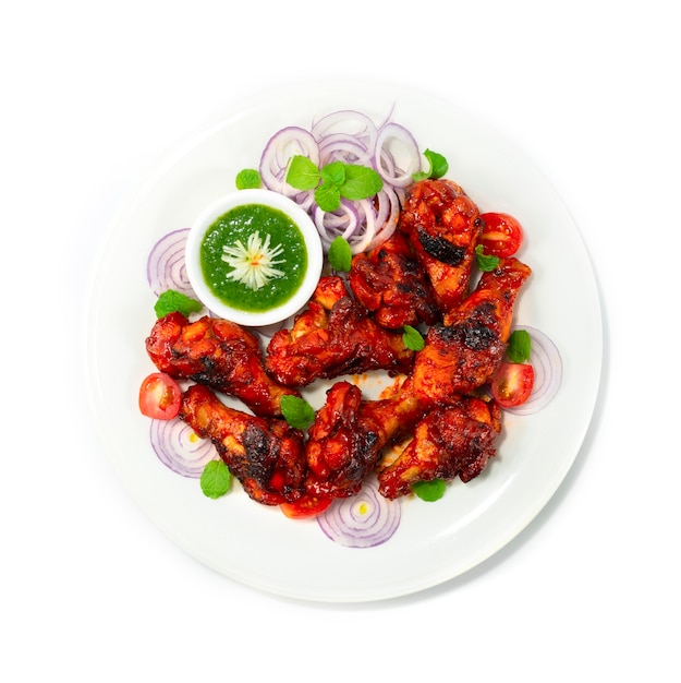 La salsa de menta servida con pollo a la parrilla Tandoori es una cena india clásica que marina alitas de pollo en una base cremosa de yogur, especias mezcladas decoradas con cebolla y vegetales.