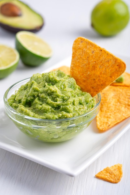 Salsa mexicana vegana de guacamole hecha de aguacate servida con nachos crujientes como refrigerio saludable