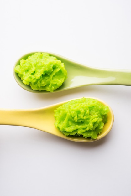 Salsa o pasta de wasabi verde en un tazón, con palillos o una cuchara sobre un fondo de colores lisos. enfoque selectivo