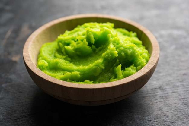 Salsa o pasta de wasabi verde en un tazón, con palillos o una cuchara sobre un fondo de colores lisos. enfoque selectivo