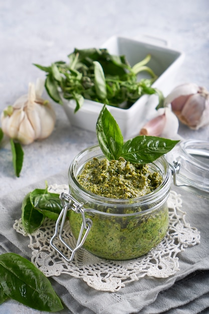 Salsa de pesto de albahaca italiana tradicional en un frasco de vidrio sobre una mesa de piedra clara