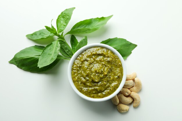 Salsa de pesto e ingredientes sobre fondo blanco.