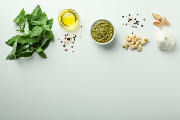 Salsa de pesto e ingredientes sobre fondo blanco.