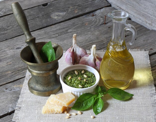 Salsa de pesto italiano e ingredientes sobre un fondo de madera oscura.