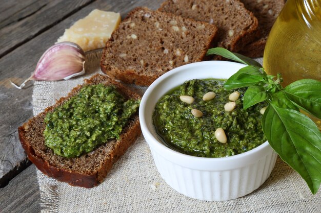 Salsa de pesto italiano y tostadas de centeno en una mesa de madera