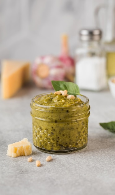 Salsa pesto en un tarro de cristal con hojas de albahaca y un trozo de queso parmesano Cocina italiana