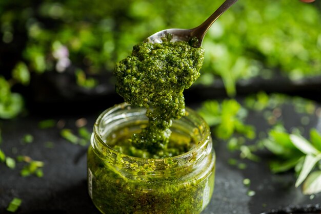 Salsa pesto en un tarro de cuchara con salsa pesto