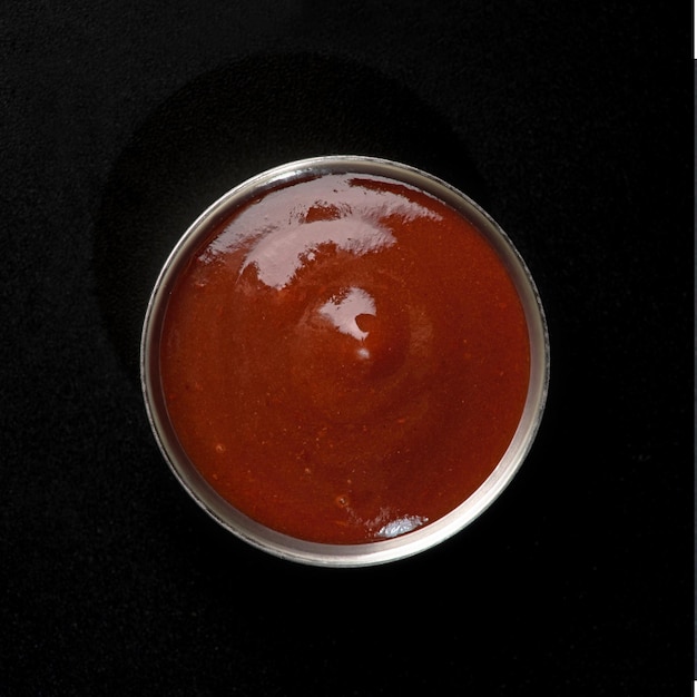 Foto salsa picante en un bote de salsa de metal sobre un fondo negro para comida rápida