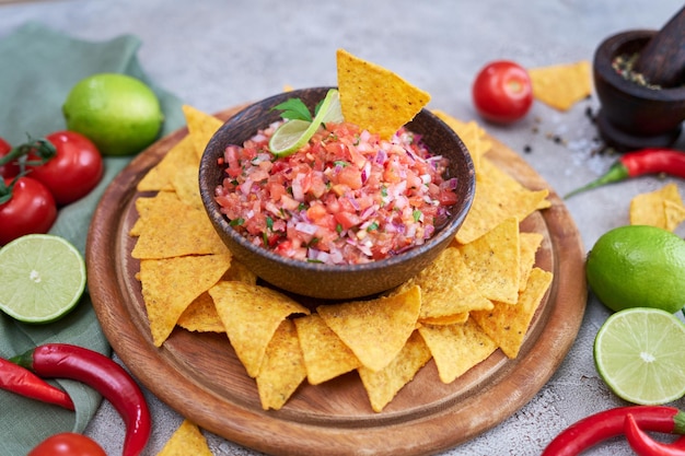 Salsa de salsa recién hecha con chips de nacho en tablero de madera