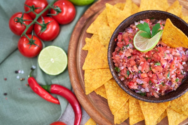 Salsa de salsa recién hecha con chips de nacho en tablero de madera