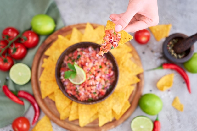 Salsa de salsa recién hecha con chips de nacho en tablero de madera