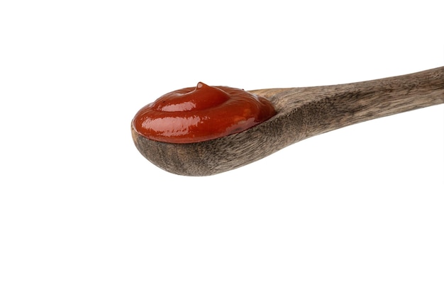 Salsa de tomate en una cuchara de madera sobre un fondo blanco.