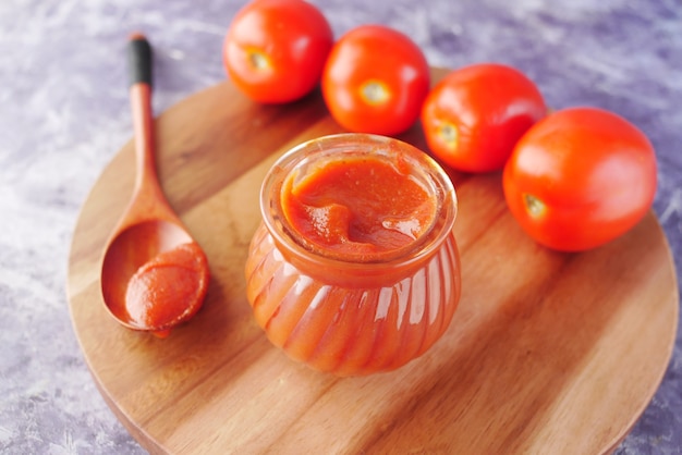 salsa de tomate en un frasco pequeño con tomate fresco en la mesa
