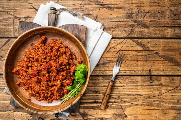 Salsa de tomate italiana tradicional boloñesa con carne picada en un plato de madera con hierbas Fondo de madera Vista superior Espacio de copia