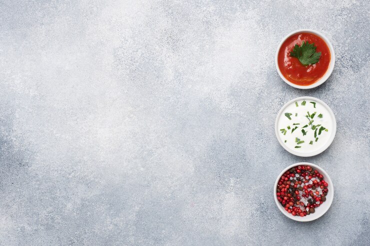Salsa de tomate mayonesa verde especias pimienta sal en placas sobre una mesa de hormigón gris con espacio de copia.