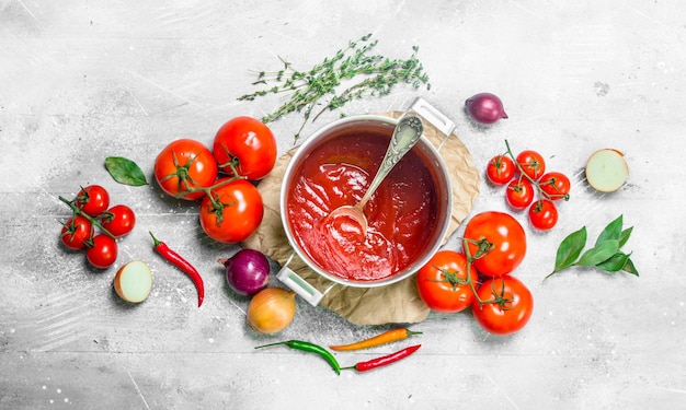 Salsa de tomate en una olla de hierbas y tomates frescos