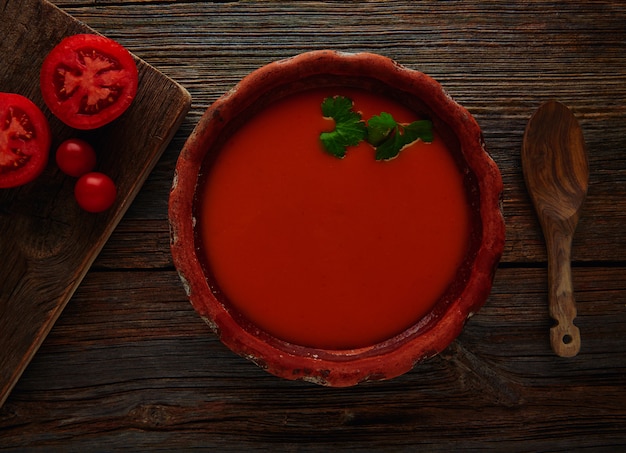 Salsa de tomate en plato de barro y madera oscura.