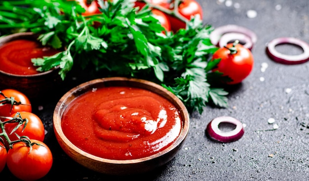 Foto salsa de tomate en un plato de madera con aros de cebolla y hierbas