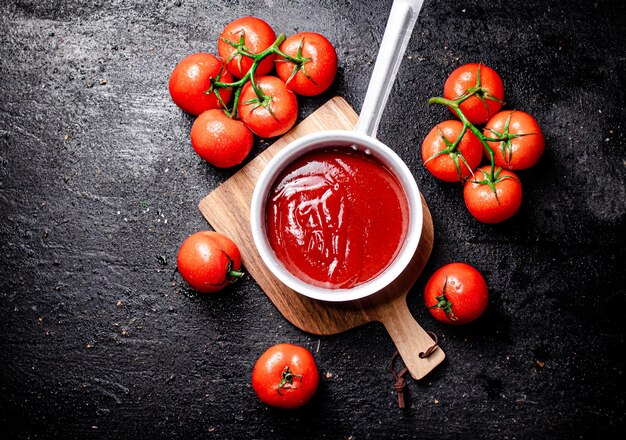 Foto salsa de tomate con rollo de salsa en una tabla de cortar de madera
