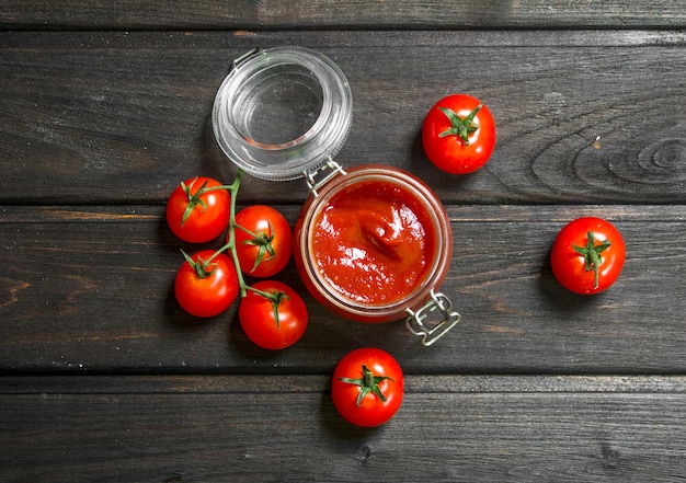 Foto salsa de tomate en un tarro con tomates cherry maduros