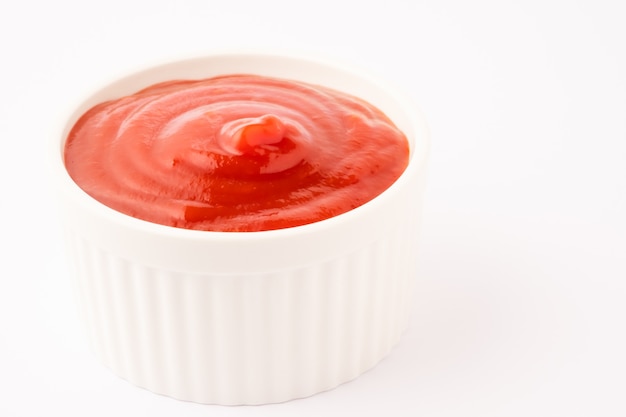 Foto salsa de tomate en un tazón de cerámica sobre fondo blanco.