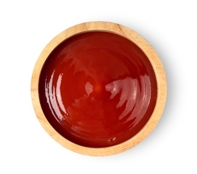 Salsa de tomate en un tazón de madera en la pared blanca.