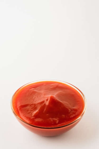 Foto salsa de tomate en un tazón de vidrio sobre fondo blanco. salsa en un tazón y copie el espacio.