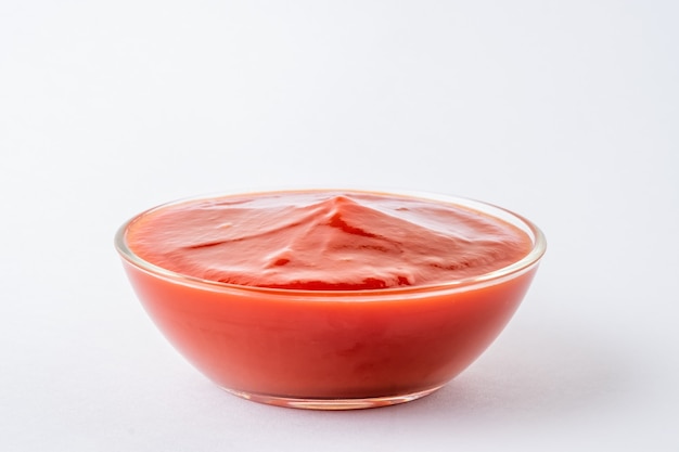 Foto salsa de tomate en un tazón de vidrio sobre fondo blanco.