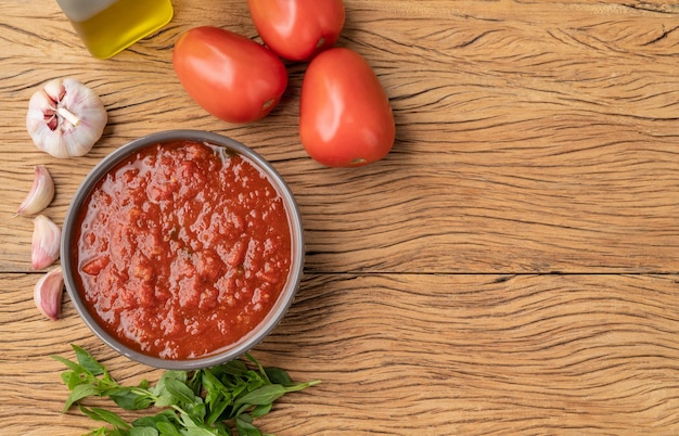 Salsa de tomate tomates ajo aceite de oliva y hierbas sobre mesa de madera con espacio para copiar