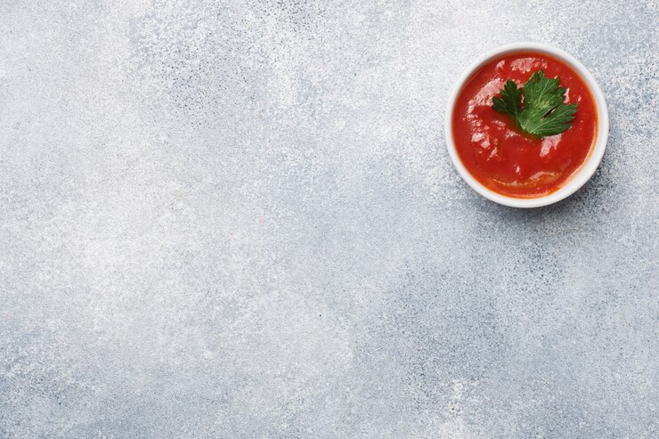 Salsa de tomate verdes en placas sobre una mesa de hormigón gris con espacio de copia.