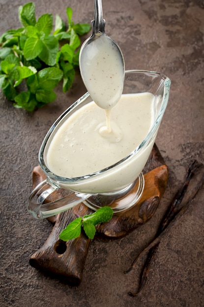 Foto salsa de vainilla con ramas de menta fresca sobre un fondo oscuro