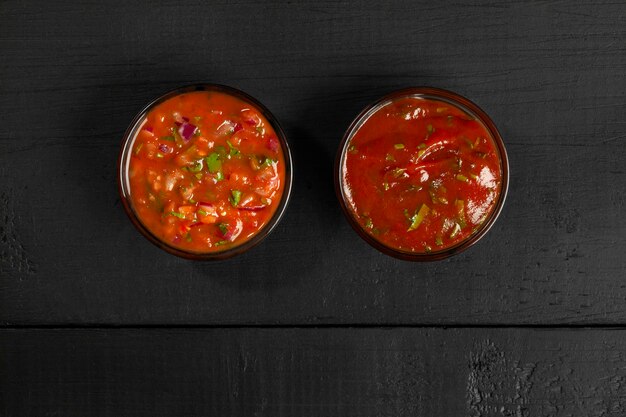 Foto salsas de tomate en cuencos de vidrio sobre fondo de madera negra