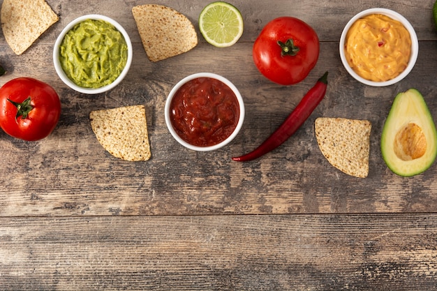 Salsas tradicionales mexicanas. Guacamole, salsa de ají y salsa de queso sobre mesa de madera