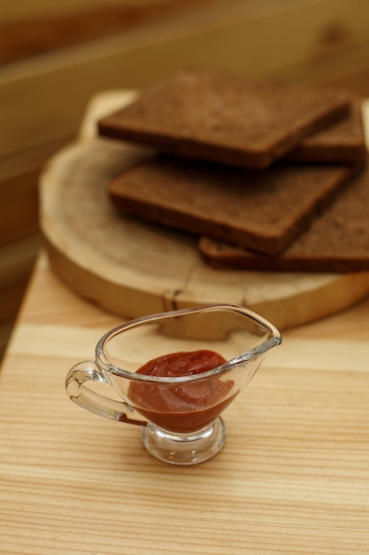 Foto salsera de vidrio con salsa de tomate en la mesa de madera