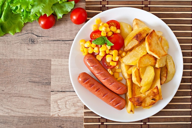 Salsicha com batatas fritas e legumes num prato