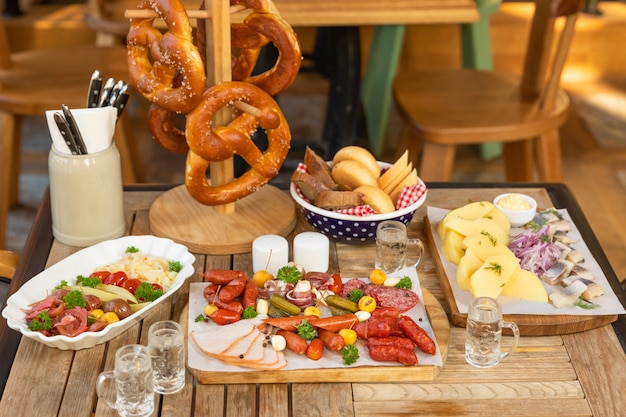 Salsicha com queijo e pepinos fermentados, salgadinhos de pretzel com vodka na mesa