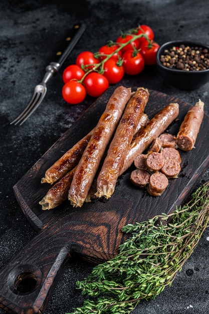 Salsicha de carne assada em uma placa de madeira com ervas e tomate.