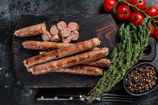 Salsicha de carne assada em uma placa de madeira com ervas e tomate